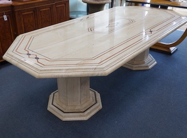 A Travertine marble dining table of elongated octagonal form on twin octagonal column supports, length 260cm, depth 120cm, height 74cm